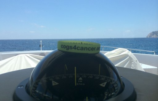 cogs for cancer wristband sitting on compass from navigation area of huge superyacht cruising in the Mediterranean 