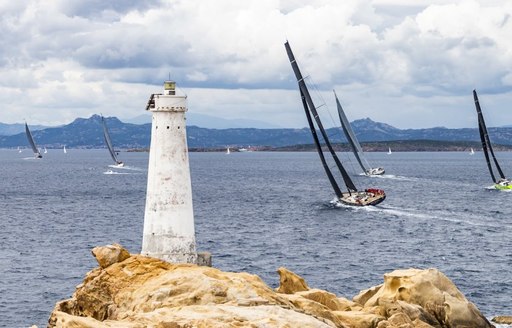 Sailing yachts at Loro Piana Superyacht Regatta rounding corner of land