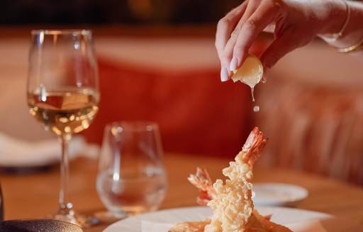Diner squeezing lemon juice onto tempura