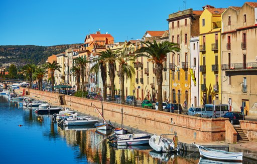 Superyachts in harbour in Sardinia, with yellow houses overlooking the canal