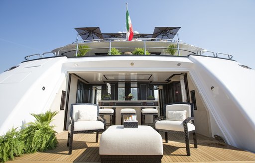 Water level view of the beach club onboard charter yacht ILLUSION V with a wetbar aft and armchairs forward