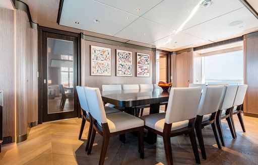 Interior dining area onboard charter yacht MOSKITO with long table surrounded by gray upholstered seats