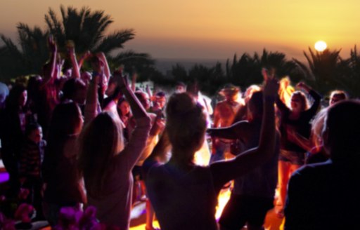 Guests on a private yacht charter in the Virgin Islands stepping onto the shore for a party at night