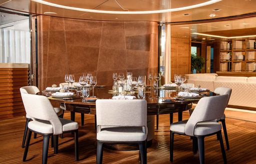 Interior formal dining area with circular table and gray seating onboard charter yacht LIFE SAGA