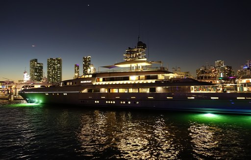 nighttime at miami yacht show, superyachts miami with skyline lit up in background