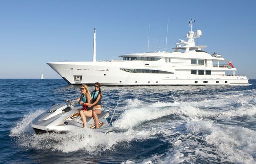 Charter yacht SPIRIT side profile with guests enjoying a jet ski