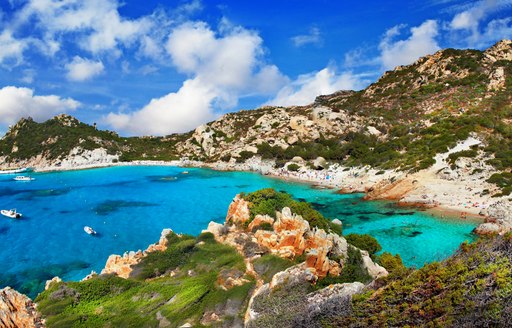 turquoise water in bay in italy, with sandy beach behind