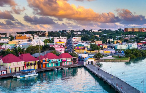 Caribbean town on edge of water with bridge stretching out and cloudy sky above