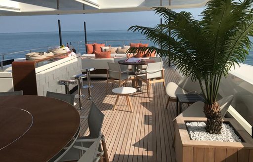 Alfresco seating area with a palm-fringed plant onboard charter yacht ANDIAMO