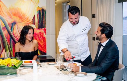 a couple being served dinner on boar their luxury charter yacht 