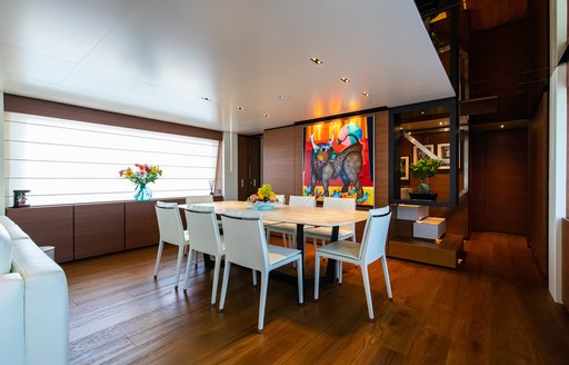 Interior dining area onboard Ferretti yacht charter 30m PENELOPE, white dining table with eight chairs with stretched window on far side