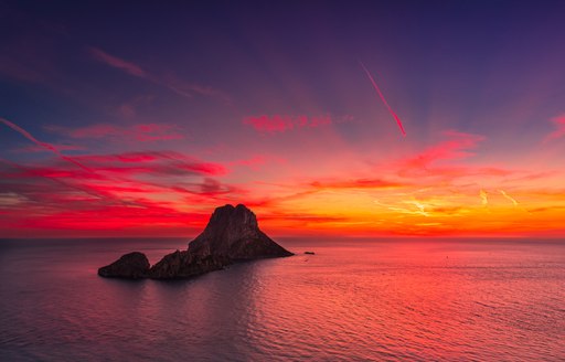 View from Ibiza at sunset to rocky outcrop and calm sea