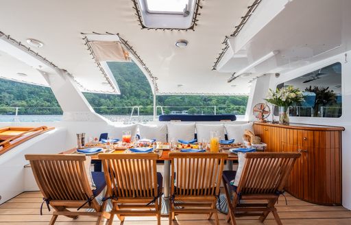 Alfresco dining table with wooden chairs laid for breakfast onboard catamaran yacht charter DOUCE FRANCE