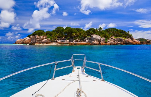 bow of a yacht heading towards an island in maldives surrounded by blue water