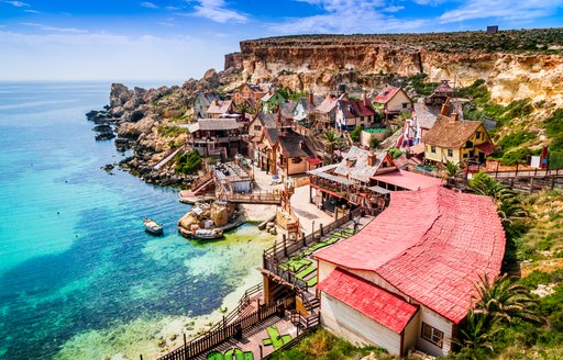 secluded beach in malta, with houses on the cliffs