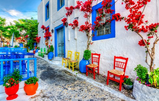 cobbled streets and blue and white taverna with red flowers growing across the plaster wall