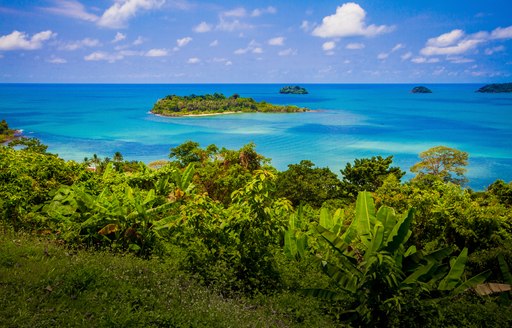 Overview of some of the Cuban coastline with lush green vegetation and a small island in the sea 