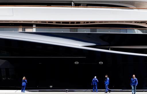 Construction team of Feadship Project 821 walking on the dock alongside the superyacht