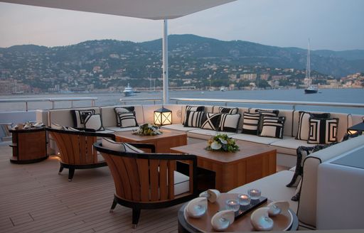 Exterior seating area with wooden coffee tables onboard charter yacht PLAN B