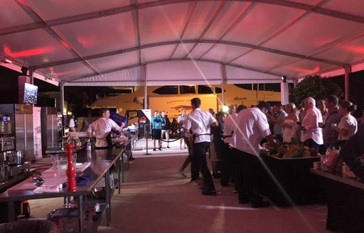 Yacht chefs cooks while show-attendees look on 