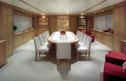 Pinewood dining room with white dining set and red accents on superyacht for charter, Ferdy