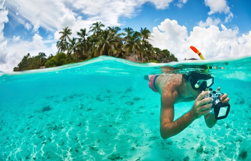 snorkeller takes pictures of the colourful underwater world in the Maldives