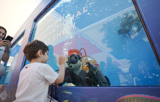 Close up view of the Dive Pool at the Dubai International Boat Show, young charter guest interacts with a diver