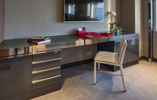 Office facilities within guest cabin onboard M/Y SERENITY, desk and stationary with white upholstered chair