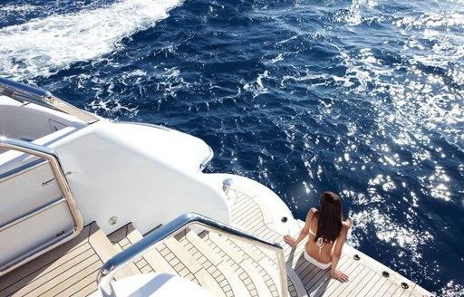 girl sits on the swim platform of luxury yacht spirit 