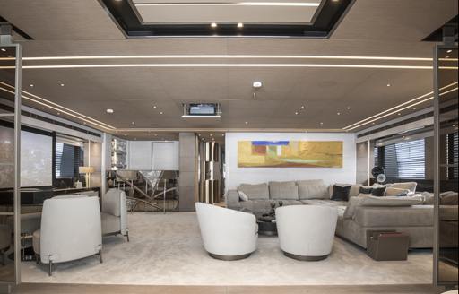 Lounge area on superyacht SEVERIN'S with sofas and chairs facing large TV on wall