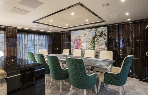 Dining area onboard charter yacht HAPPY ME, long table surrounded by green seating