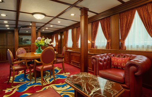 Interior seating area onboard charter yacht SEAGULL II, with red leather armchair and circular table