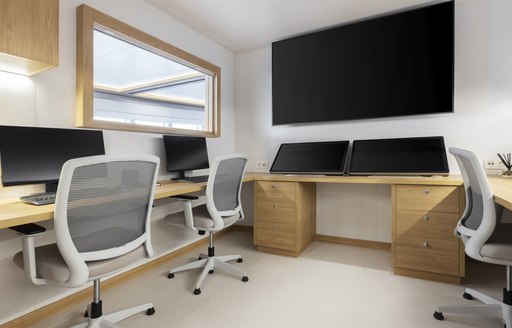 Overview of an office onboard charter yacht WAYFINDER, several computer stations with flat screen monitor on wall.