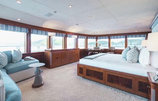 Overview of master cabin onboard superyacht charter TITANIA with central berth and large stretch of windows