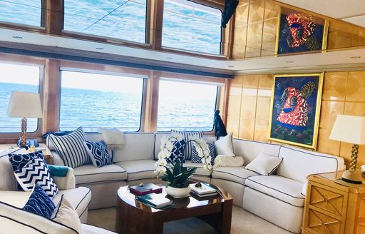 Interior seating area with plush sofas and nautical themed cushions by large windows onboard charter yacht LADY AZUL