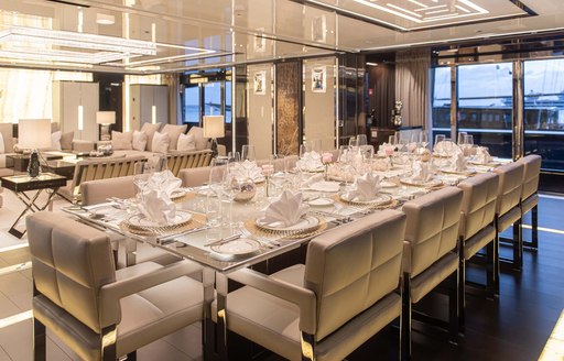 Interior dining area onboard charter yacht RESILIENCE, long table with surrounding pale gray seats