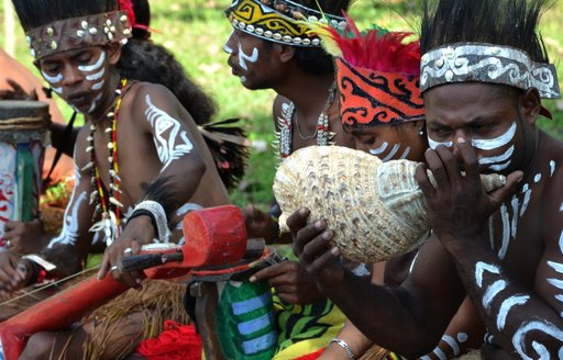 locals in raja ampat islands blowing into a shell