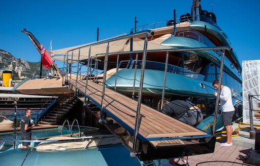 Aft view of charter yacht KENSHO at Monaco Yacht Show with ramp for access and crew tending to tenders and equipment