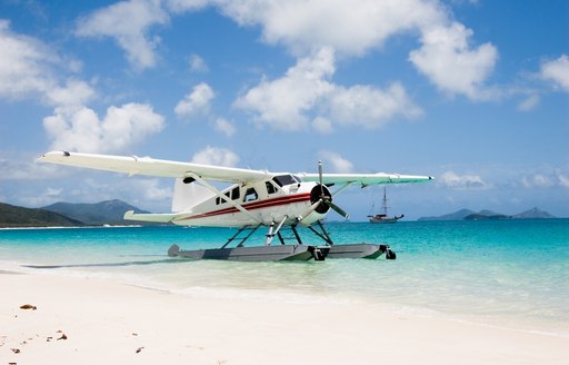 a seaplane lands on the dazzling white sands of a beach in the Whitsundays