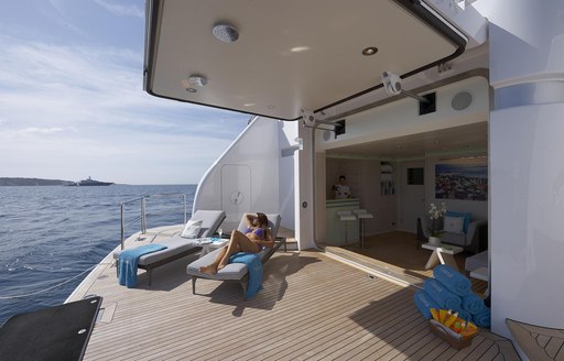 Guests relax on sunloungers positioned on the swim platform of superyacht TITANIA