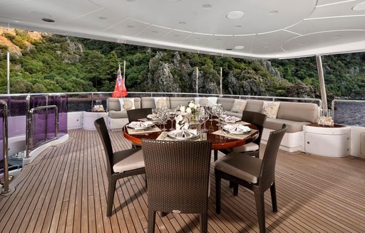 Alfresco dining table and seats on exterior deck of charter yacht QUEST R