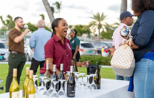 Drinks server at the Bahamas Charter Yacht Show laughing with visitors