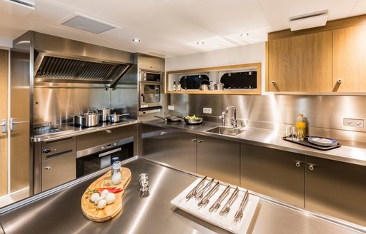 Stainless steel galley of Game Changer yacht with knives and food being prepared in foreground