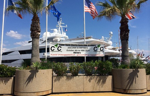 International Yacht Club of Antibes cogs for cancer sign next to superyachts in french riviera harbour