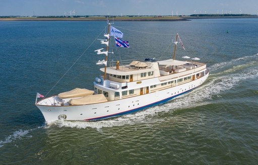 ISTROS motor yacht hull on sea with shore in foreground and flag flying