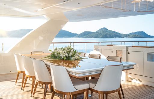 Alfresco dining option onboard charter yacht SUNRISE with a long table surrounded by white upholstered chairs