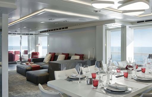 THE DELUXE AND SLEEK SINING ARANGEMENT IN THE MAIN SALON OF CHARTER YACHT home OVERLOOKING THE WATER FROM HER large windows