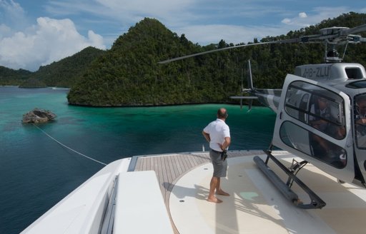 A man stands on the helideck of a superyacht looking out across Indonesia