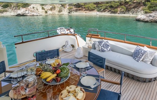 Aft deck onboard boat charter ESTIA POSEIDON with white seating an a table set for a meal