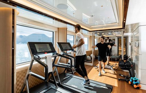 Overview of the gym onboard superyacht charter EXCELLENCE with charter guests using the equipment